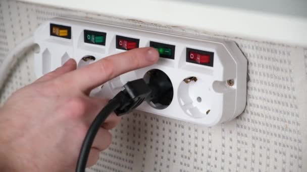 The man pulls the plug out of the adapter socket and turns off switch. — Vídeo de Stock