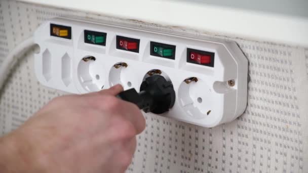 The man inserts the plug into adapter socket and presses the switch. — Stock videók