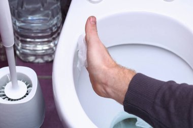 Adam peçeteyle tuvaleti siliyor. Evin temizliği, banyo..