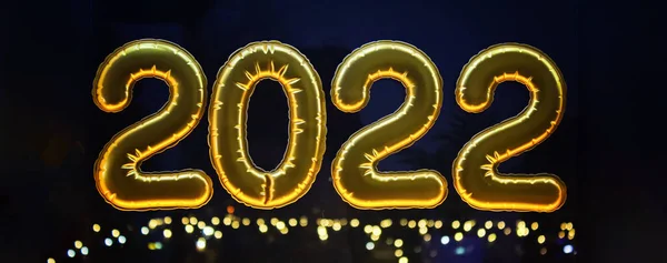 Globos inflables dorados de la hoja números 2022 en ventana contra el fondo de la ciudad de la noche, en —  Fotos de Stock