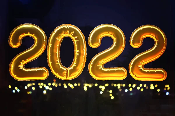 Globos inflables dorados de la hoja números 2022 en ventana contra el fondo de la ciudad de la noche, en —  Fotos de Stock