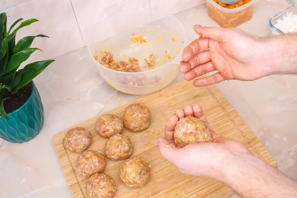 A man sculpts lazy cabbage rolls from minced meat, cabbage, rice. The man forming meat balls. — Fotografia de Stock