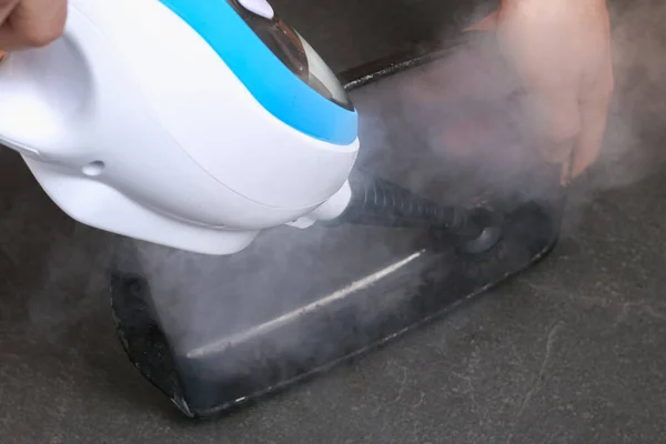 Un homme nettoie un plat de cuisson sale avec une épaisse couche de carbone avec une buse spéciale de nettoyage à vapeur — Photo