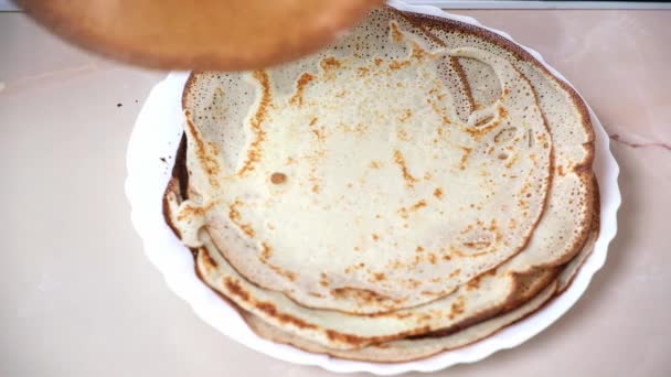 The woman puts the pancake into a pile. Crepes are fried in a skillet on the stove. Pancake baking — стоковое видео