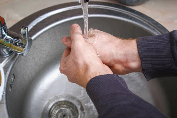 A man washes his hands with soap in kitchen sink after washing potatoes. — Fotografia de Stock