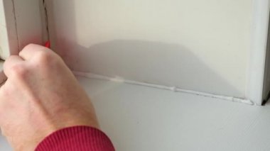 Adam cam ve pervazın arasındaki silikon dolguyu plastik bir spatulayla kaldırıyor. Güzel.