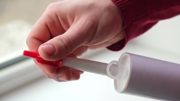 O homem remove a tampa protetora do tubo de selante de silicone para posterior aplicação. — Vídeo de Stock