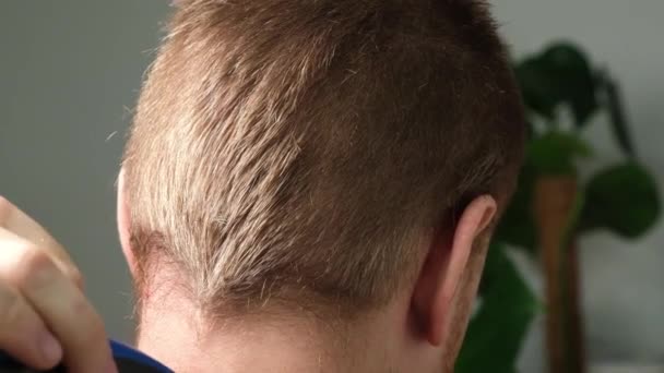 En man klipper sig med en elektrisk klippare hemma. Frisyr hemma. Besparingar på en frisör. — Stockvideo