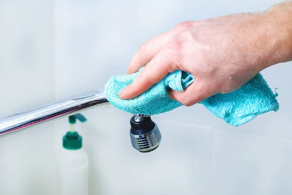 A man wipes a mixer tap, faucet with a rag. Cleaning of the house, bathroom. — Fotografia de Stock