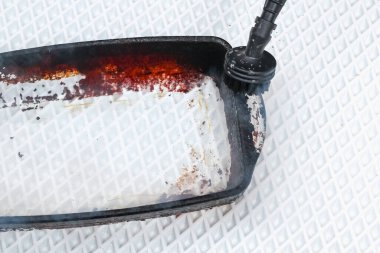 Bir adam özel bir buhar temizleme hortumuyla kalın bir karbon katmanıyla kirli bir yemek tabağını temizler.