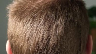 Evde bir adam elektrikli makasla saçını kestiriyor. Ev tıraşı. Bir kuaförde tasarruf.