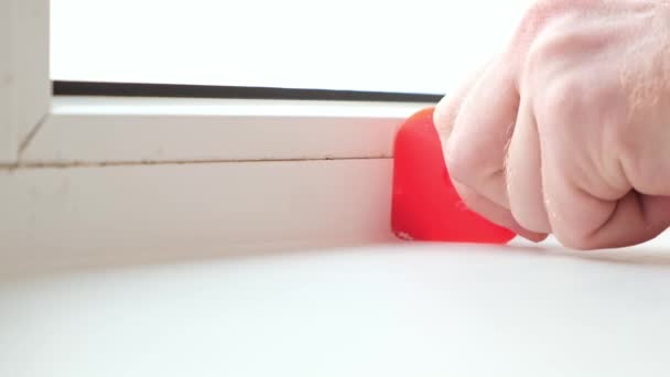 The man removes the silicone sealant between the window and sill with a rubber spatula. A beautiful — Stock Video