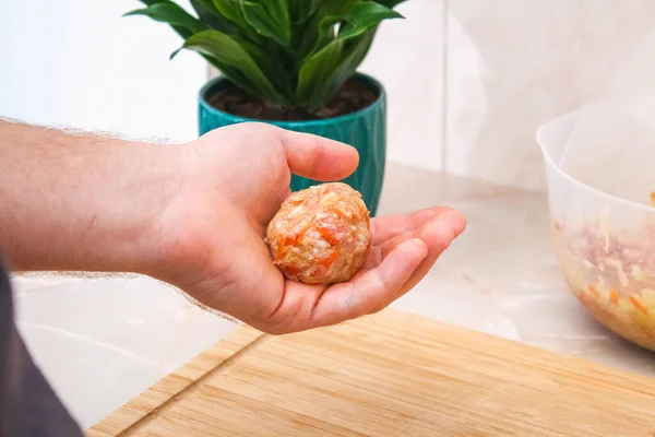 A man sculpts lazy cabbage rolls from minced meat, cabbage, rice. The man forming meat balls. — Fotografia de Stock