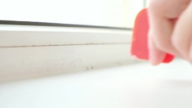 Adam cam ve pervazın arasındaki silikon dolguyu plastik bir spatulayla kaldırıyor. Güzel.