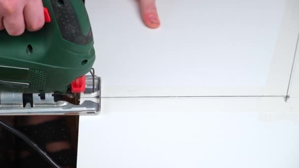 A man cuts a window sill from board for a window using an electric jigsaw for work. — Stock Video