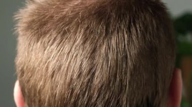 Evde bir adam elektrikli makasla saçını kestiriyor. Ev tıraşı. Bir kuaförde tasarruf.