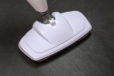 Bir adam siyah porselen taşları buhar paspası ile yıkıyor. Mikropları öldürmek, temiz zemin, arındırma..