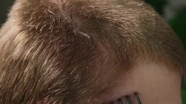 Egy férfi levágatja a haját egy elektromos ollóval otthon. Házi hajvágás. Megtakarítások egy fodrászon. — Stock videók