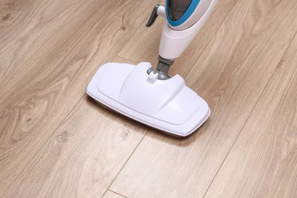 A man washes laminate flooring with steam mop. Killing germs, clean floor, decontamination. — Stock Photo, Image