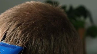 Evde bir adam elektrikli makasla saçını kestiriyor. Ev tıraşı. Bir kuaförde tasarruf.