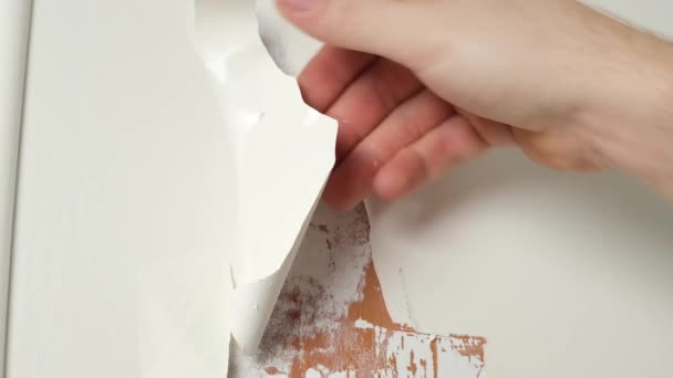 Un homme enlève une vieille peinture en émail blanc de la porte en bois avec un sèche-cheveux de construction et une spatule — Video