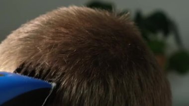 Evde bir adam elektrikli makasla saçını kestiriyor. Ev tıraşı. Bir kuaförde tasarruf.