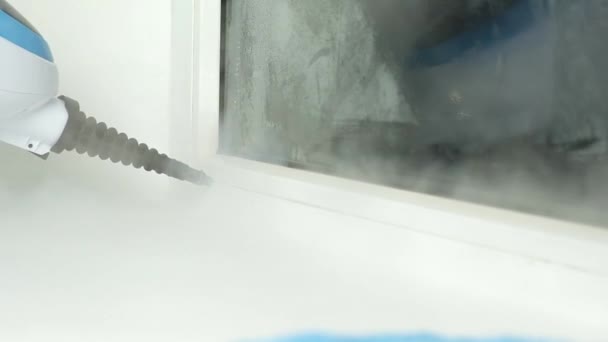 Un hombre lava las articulaciones de la ventana con un limpiador de vapor. Limpiador de vapor para limpiar la casa — Vídeo de stock