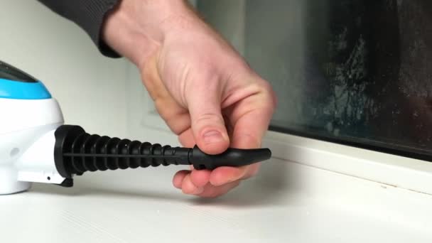 A man washes the joints on window with a steam cleaner. Steam cleaner for cleaning the house — Stock Video