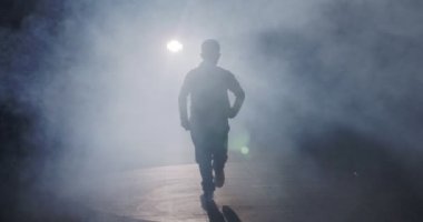 Hafif ve dumanlı ağır çekimde hip hop dansı yapan bir kadın dansçının silueti