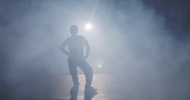 Hafif ve dumanlı ağır çekimde hip hop dansı yapan bir kadın dansçının silueti