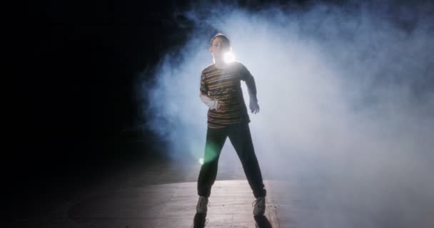 Νεαρή χορεύτρια χορεύει hip hop σε αργή κίνηση με φόντο το φως και τον καπνό — Αρχείο Βίντεο