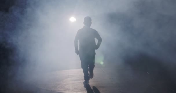 Silhueta de uma dançarina realizando dança hip hop em câmera lenta com luz e fundo de fumaça — Vídeo de Stock