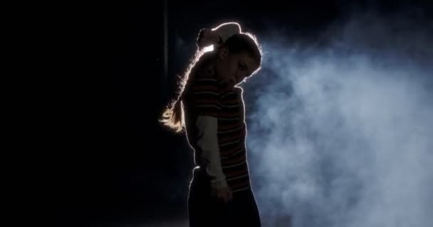 Σιλουέτα μιας χορεύτριας που χορεύει χιπ χοπ με φόντο το φως και τον καπνό — Αρχείο Βίντεο