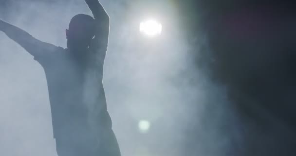 Silhueta de uma dançarina realizando dança hip hop em câmera lenta com luz e fundo de fumaça — Vídeo de Stock