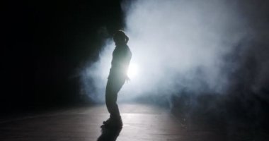 Hafif ve dumanlı ağır çekimde hip hop dansı yapan bir kadın dansçının silueti