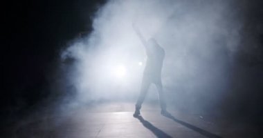 Genç bayan dansçı ışık ve dumanla vahşi hip hop dansı yapıyor.