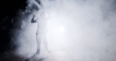 Hafif ve dumanlı ağır çekimde hip hop dansı yapan bir kadın dansçının silueti