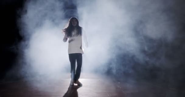 Νεαρή χορεύτρια που χορεύει άγρια χιπ χοπ με φόντο το φως και τον καπνό — Αρχείο Βίντεο