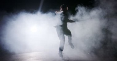 Hafif ve dumanlı ağır çekimde hip hop dansı yapan bir kadın dansçının silueti