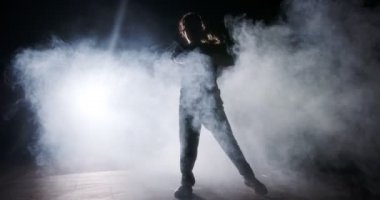 Hafif ve dumanlı ağır çekimde hip hop dansı yapan bir kadın dansçının silueti