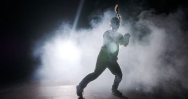 Hafif ve dumanlı ağır çekimde hip hop dansı yapan bir kadın dansçının silueti