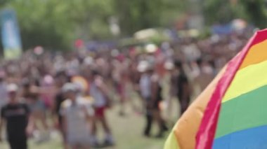 LGBTQ gökkuşağı bayrağı arka planda insanlarla ağır çekimde dalgalanıyor