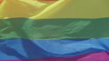 LGBTQ gökkuşağı bayrağı arka planda insanlarla ağır çekimde dalgalanıyor