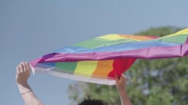 LGBTQ gökkuşağı bayrağı ana parti sırasında ağır çekimde sallanıyor.