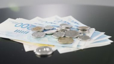 Bills and coins of New Israeli Shekels rotating on reflective surface