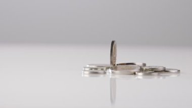 Coins of New Israeli Shekels rotating on reflective surface