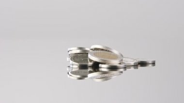 Coins of New Israeli Shekels rotating on reflective surface