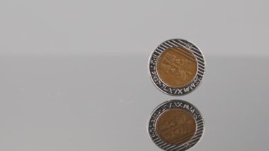 New Israeli Shekels coins falling on a reflective surface