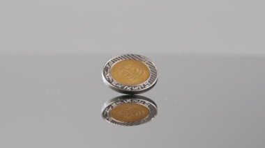 New Israeli Shekels coins falling on a reflective surface