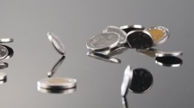 New Israeli Shekels coins falling on a reflective surface